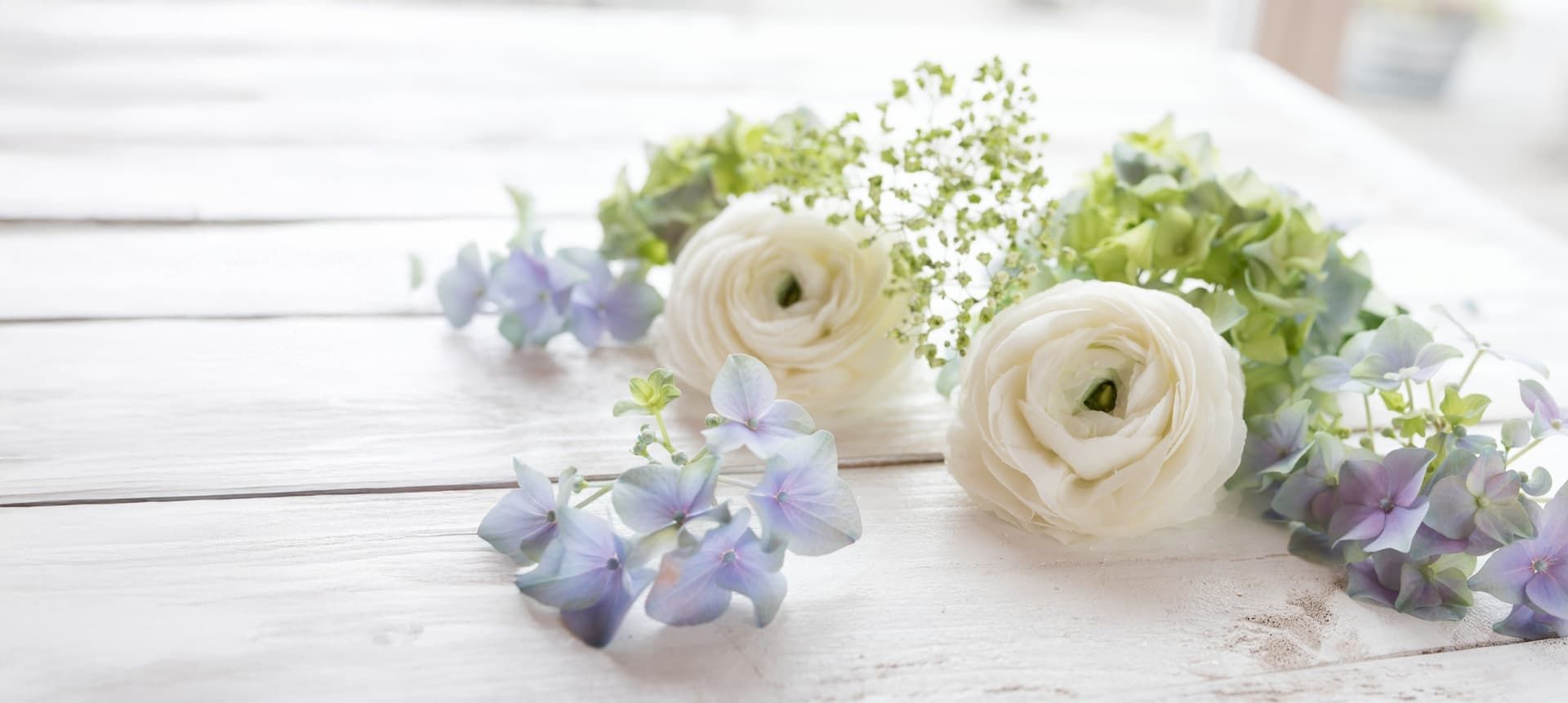 Weiße und blaue Blumen liegen auf Holz
